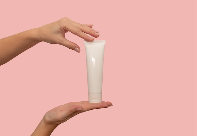 Hands hold a white container with cosmetic cream For body care On a pink background