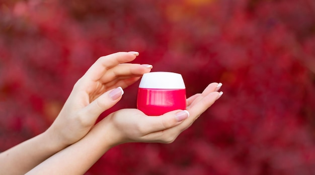 Hands holding and applying cream jar for skincare product proposal