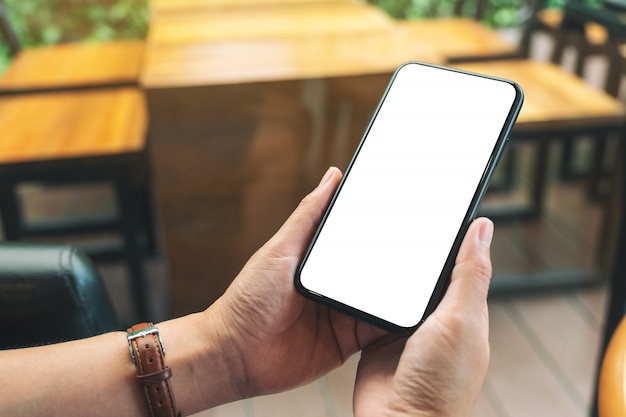 hands holding black mobile phone with blank desktop screen