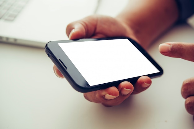 Hands holding blank screen mobile in desk work.