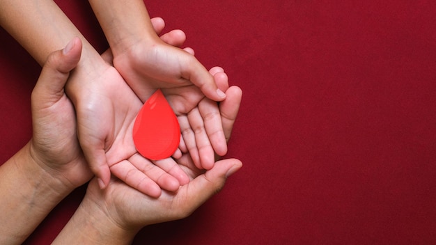 Hands holding blood drop give blood donation blood transfusion world blood donor day world hemophilia day concept