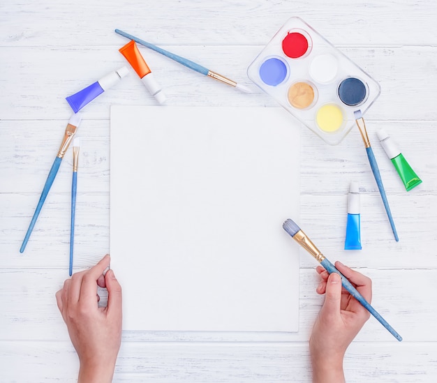 Hands holding a brush above an empty white paper sheet