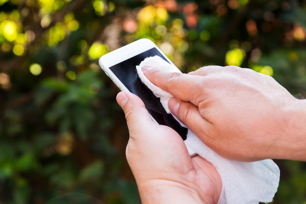 Hands holding and cleaning a cell phone