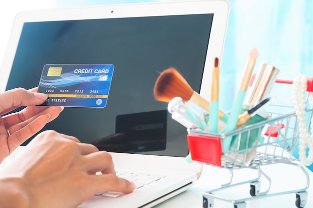 Hands holding credit card and using laptop computer.