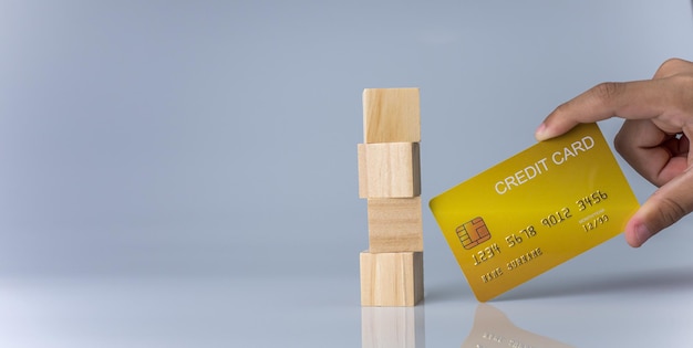 Hands holding credit cards and wooden cube blocks stacked on top of each other .