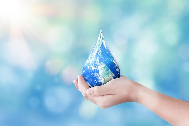 Hands holding global in drop shape on blurred nature background World day for water and sustain for earth concept Elements of this image furnished by NASA