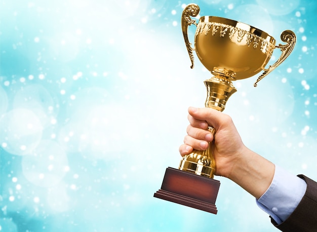 Hands holding golden trophy on background