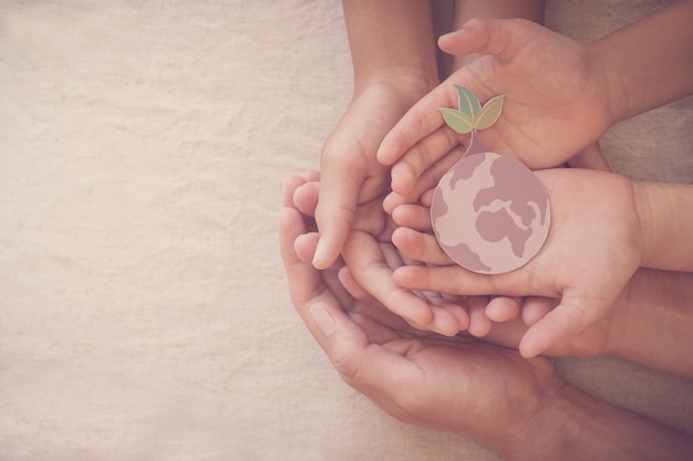 Hands holding growing tree on earth