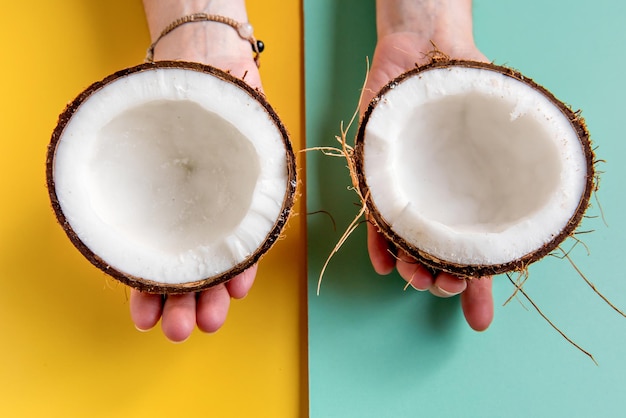 Hands holding halfcut coconut on green and yellow background