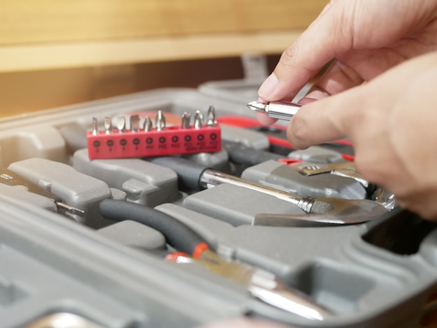 Hands holding handles, turning heads of the screwdriver and changing heads of various sizes in the toolbox.