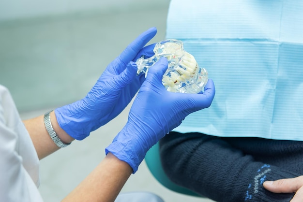 Hands holding a jaw model doctor in blue gloves progress of dental implantology