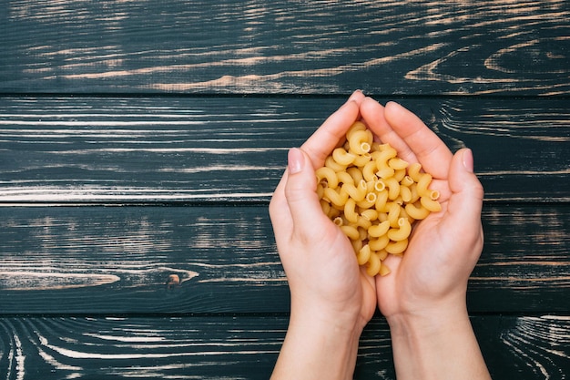 Hands holding macaroni Pasta in female hands