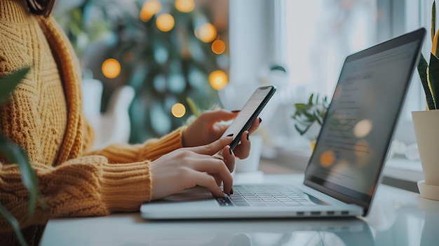 Hands Holding Mobile Phone and Typing on Laptop with Bright White Background