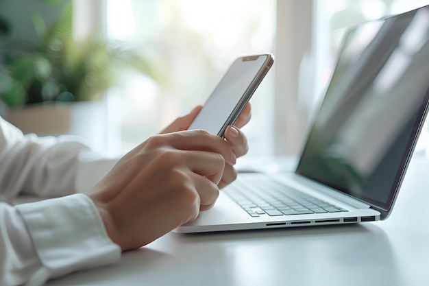 Hands Holding Mobile Phone and Typing on Laptop with Bright White Background