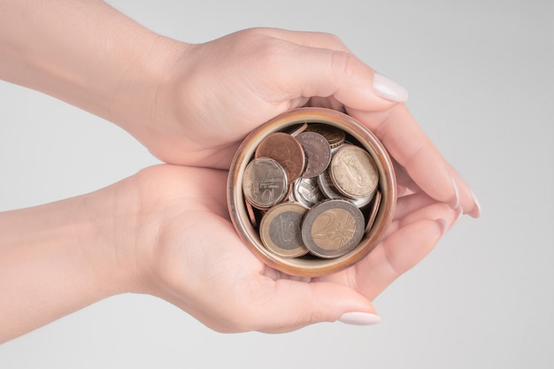 Hands holding money jar on white background