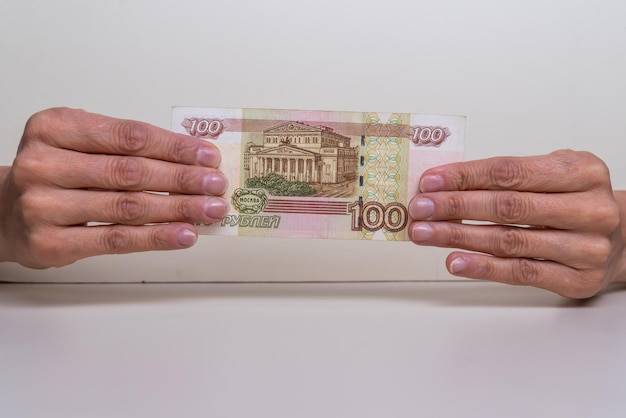 Hands holding one hundred russian rubles close up