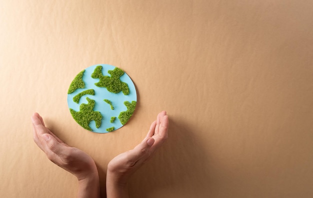 Hands holding paper earth with grass on brown background World environment day earth day and save earth concept