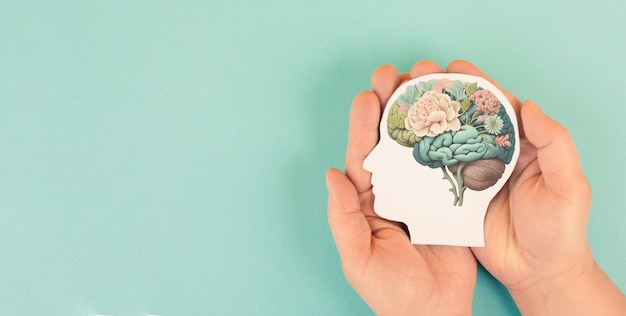 Hands holding paper head, human brain with flowers, self care and mental health concept, positive