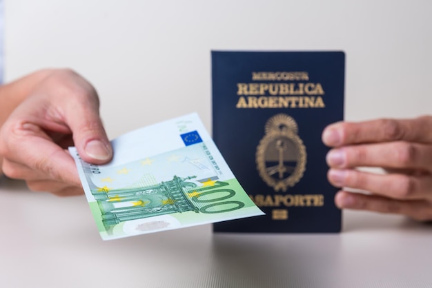 Hands holding passport and several banknotes from different countries