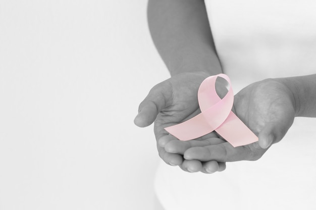 hands holding pink ribbon curl on white isolated fabric with copy space