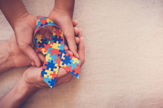 Hands holding puzzle ribbon for autism awareness