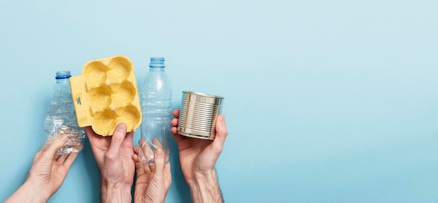 Hands holding recycling rubbish against a blue background