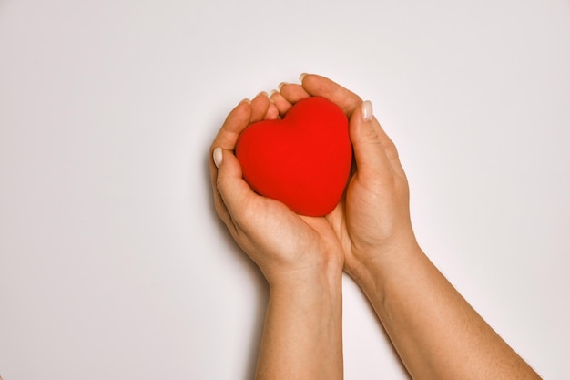 Hands holding red heart health care love organ donation praying concept