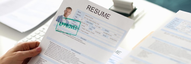 Hands holding resume of man for employment with stamp approved closeup