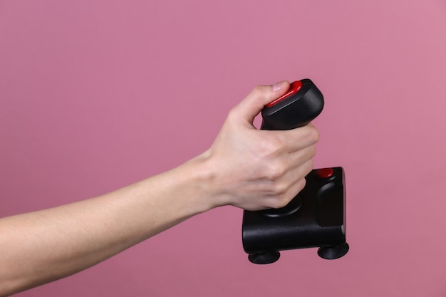 Hands holding retro joystick on pink background. Old gaming. 80s retro wave