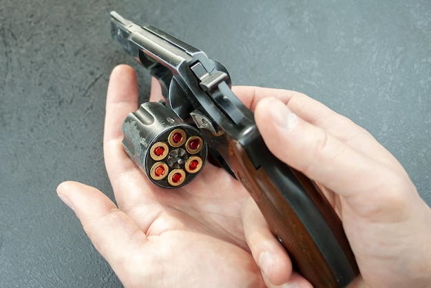 Hands holding a revolver with an open drum with 9 mm cartridges