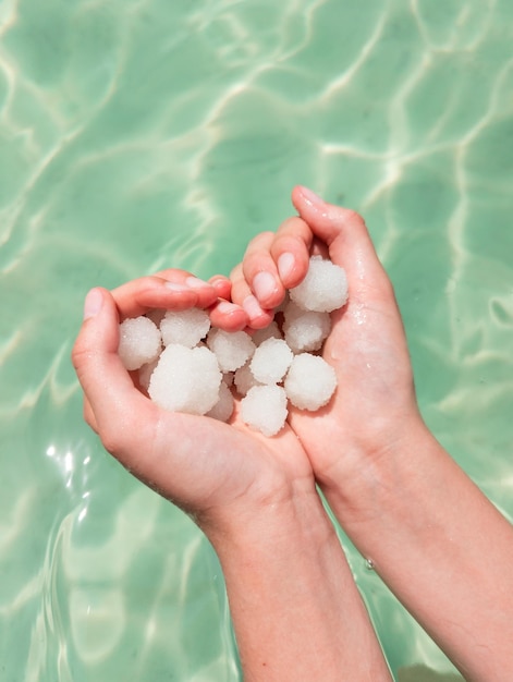 Hands holding sea salt crystals heartsaped on sea water background