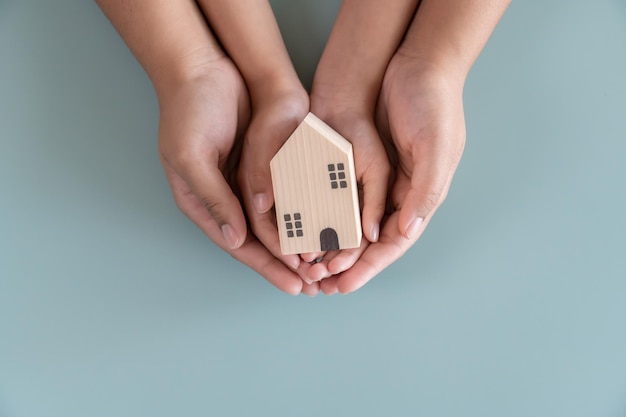 Hands holding small wooden house concept of protection or savings for property real estate