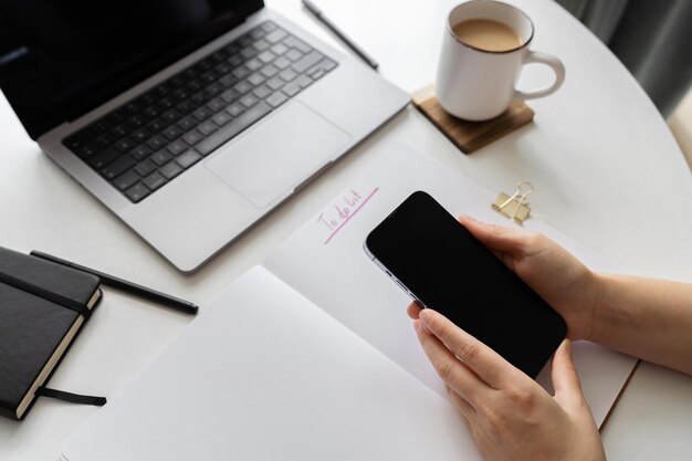 Photo hands holding smartphone near laptop screen