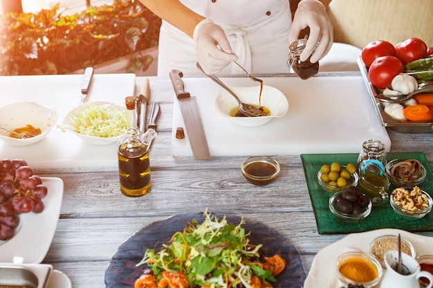 Hands holding spoon and jar. Sauce pouring into bowl. Chef mixing food ingredients. Gourmets will be happy.