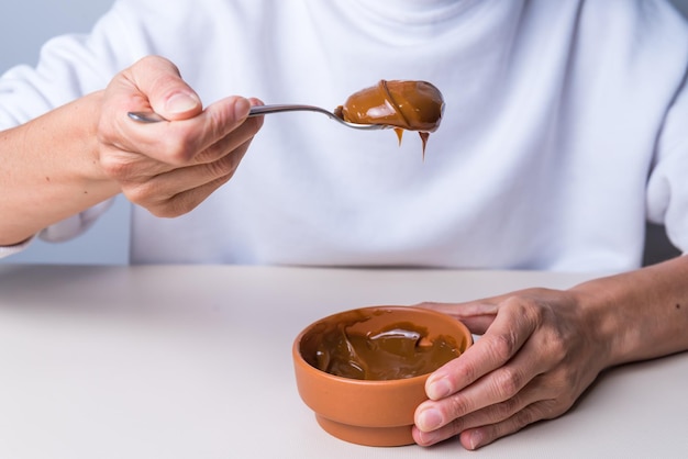 Hands holding spoon with dulce de leche