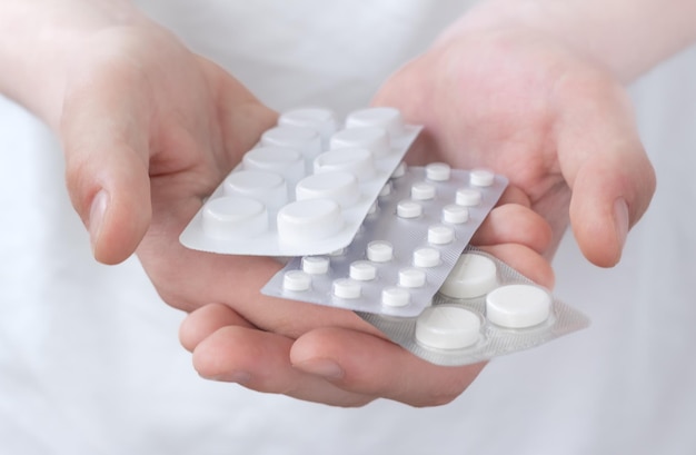 Hands holding a stack of many different pills