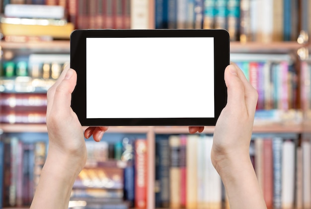 Photo hands holding tablet pc in front of books