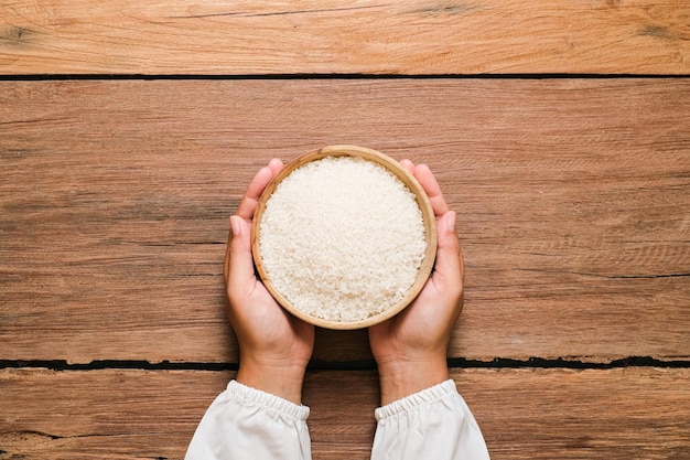 Hands holding a wooden bowl of rice grains for zakat Islamic zakat concept