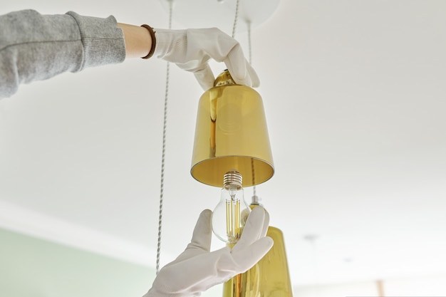 Hands installing LED bulb in lamp, chandelier