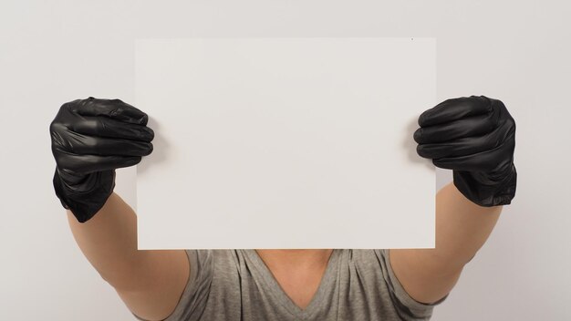 hands is holding the A4 paper and wear latex glove with gray t shirt on white background