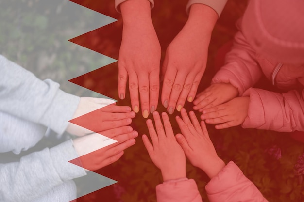 Hands of kids on background of Bahrain flag Bahraini patriotism and unity concept