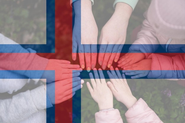 Hands of kids on background of Faroe Islands flag Faroe Islander patriotism and unity concept