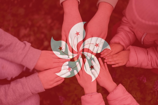 Hands of kids on background of Hong Kong flag Hongkonger patriotism and unity concept