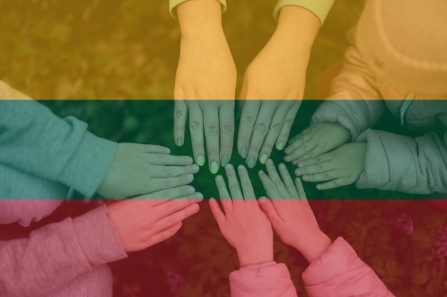 Hands of kids on background of Lithuania flag Lithuanian patriotism and unity concept