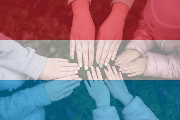 Hands of kids on background of Luxembourg flag Luxembourger patriotism and unity concept