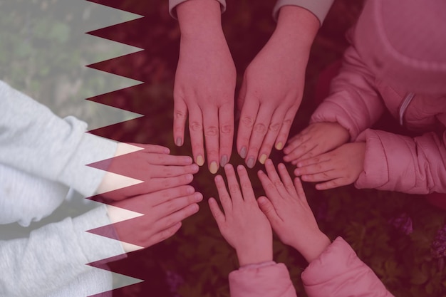 Hands of kids on background of Qatar flag Qatari patriotism and unity concept