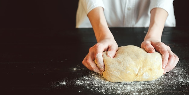 Hands knead the dough