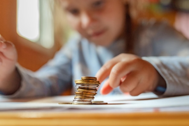 The hands of a little girl play with coins and money First lessons in finance Accumulation Credit kid saving money for the future concept