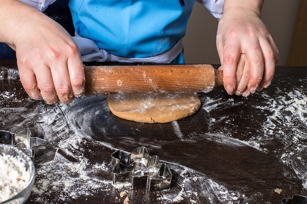 Hands of little girl sheeting dough with rolling pin