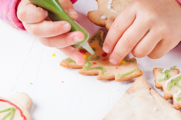 Hands of little girl, who draws on gingerbread cookies